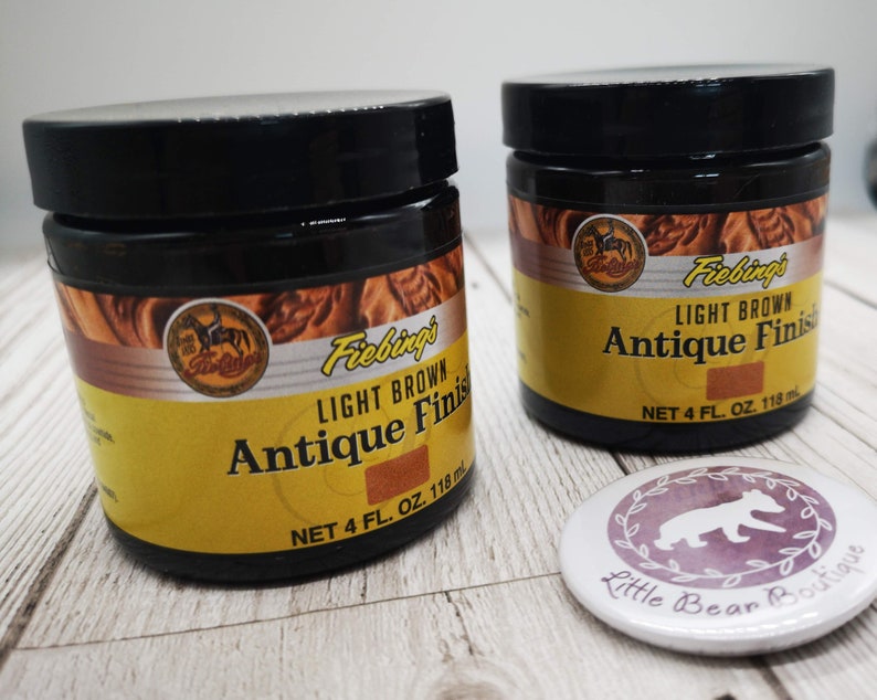 May include: Two 118ml bottles of Fiebing's Light Brown Antique Finish leather dye. The bottles are on a light wood surface with a small round sticker that says "Little Bear Boutique".
