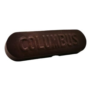 以下が含まれることがあります： 「COLUMBUS」と刻印された、濃い茶色の靴磨きバー