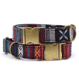 Op de afbeelding: Twee hondenhalsbanden met een kleurrijk geweven patroon en messing gespen. De bovenste halsband is zwart met witte en rode accenten. De onderste halsband is zwart met blauwe, rode en oranje accenten.