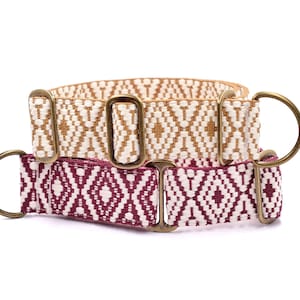 Op de afbeelding: Twee hondenhalsbanden met geometrische patronen. De bovenste halsband is beige met een wit geometrisch patroon. De onderste halsband is bordeauxrood met een wit geometrisch patroon. Beide halsbanden hebben gouden metalen beslag.