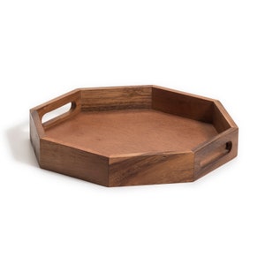 May include: Octagonal wooden serving tray with two handles. The tray is made of dark brown wood and has a natural finish.