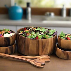 Puede incluir: Un juego de cuatro ensaladeras de madera con un juego de cucharas para ensalada de madera. Las ensaladeras están hechas de madera de acacia y son de varios tamaños. Las ensaladeras están llenas de lechuga, tomates, pepinos y otras verduras.
