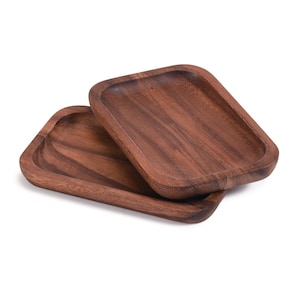 May include: Two wooden serving trays, one stacked on top of the other. Both trays are rectangular with rounded corners and a dark brown wood grain.