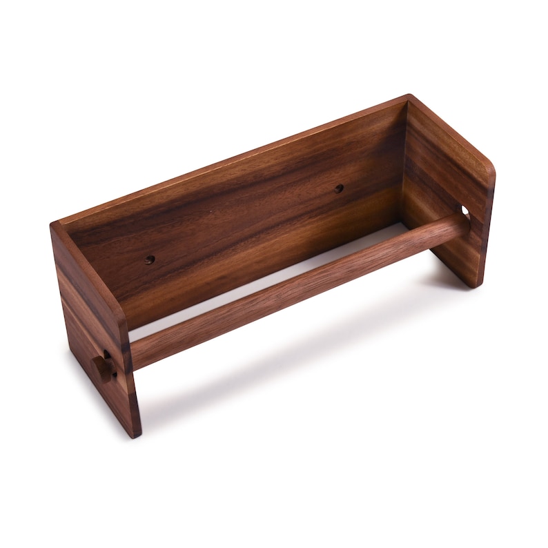 May include: A wooden wall-mounted paper towel holder with a dark brown finish. The holder has a simple design with a single bar for holding the towel.