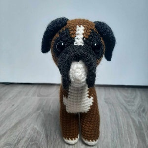 Op de afbeelding: Een bruin en wit gehaakt boxerhond knuffeldier met zwarte oren en zwarte ogen.