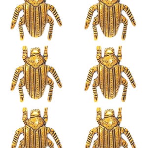 May include: Six gold-coloured beetle figurines with black stripes and a textured surface. The beetles are arranged in two rows of three.