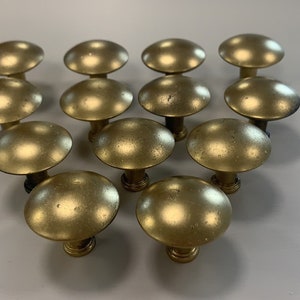 May include: A collection of 14 gold-toned cabinet knobs with a mushroom-shaped design.