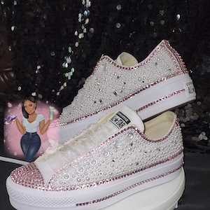 Puede incluir: Zapatillas Converse blancas con pedrería rosa y blanca. Las zapatillas están cubiertas de pequeñas pedrerías redondas y tienen un borde rosa.