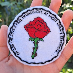May include: White embroidered patch with a red rose and black text that reads "Oh God the joys I feel in hindsight, at night when I reminisce..."