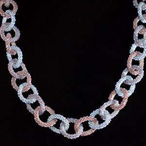 May include: A necklace made of linked, beaded loops. The loops are alternating colors of light blue and pink.