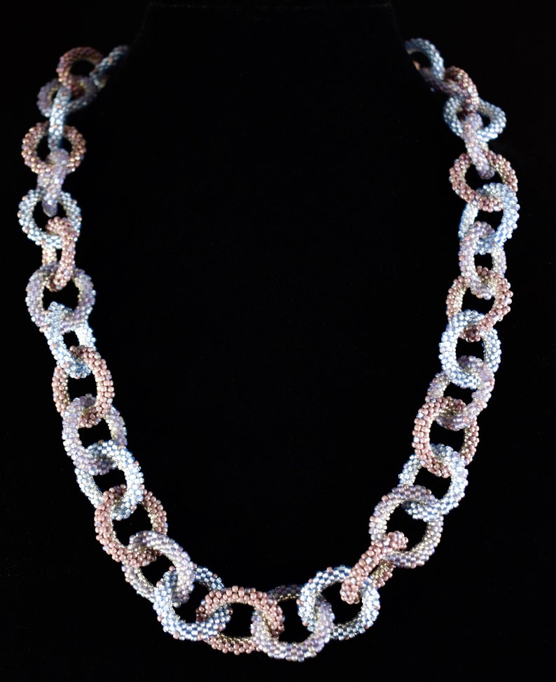 May include: A silver and rose gold beaded necklace with a chain link design.