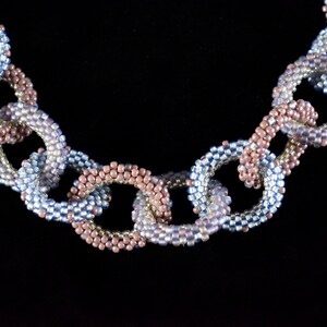May include: A beaded necklace with alternating blue and pink links, creating a chain-like design.