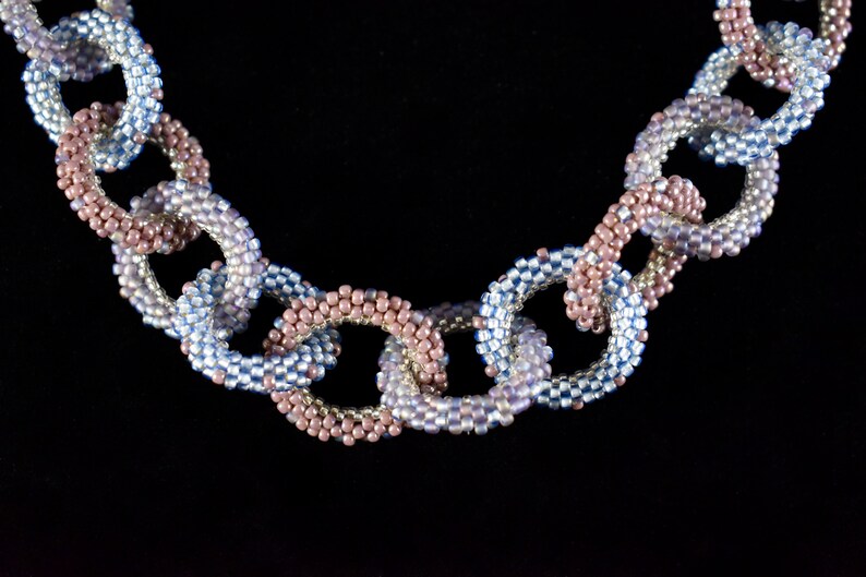 May include: A beaded necklace with alternating blue and pink links, creating a chain-like design.