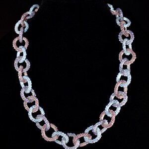 May include: A beaded necklace made of linked circles in shades of blue and purple.