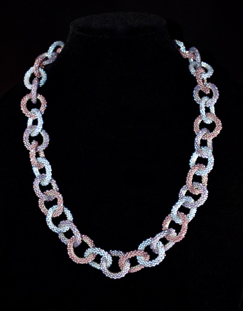 May include: A beaded necklace made of linked circles in shades of blue and purple.