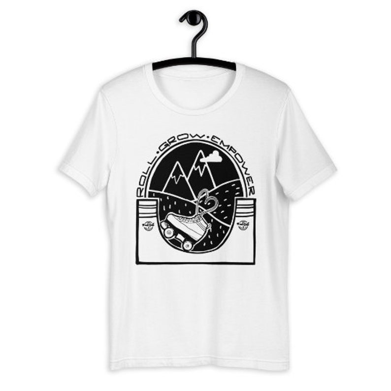 May include: White t-shirt with a black graphic of a roller skate going uphill with mountains in the background. The text "Roll. Grow. Empower" is around the graphic.