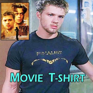 Può includere: Una maglietta blu navy con la scritta "FINALIST" in oro sopra una grafica dorata. L'immagine include anche un poster cinematografico e le parole "MOVIE T-SHIRT" in turchese.