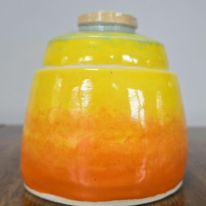 Könnte beinhalten: Eine gelbe und orangefarbene Keramikdose mit weißem Rand. Die Dose hat einen Farbverlauf von Gelb nach Orange.