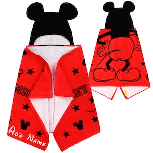 Op de afbeelding: Rode badhanddoek met capuchon met een zwart Mickey Mouse-ontwerp. De handdoek heeft een wit interieur en heeft zwarte sterren en de tekst "Mickey" en "Mouse".