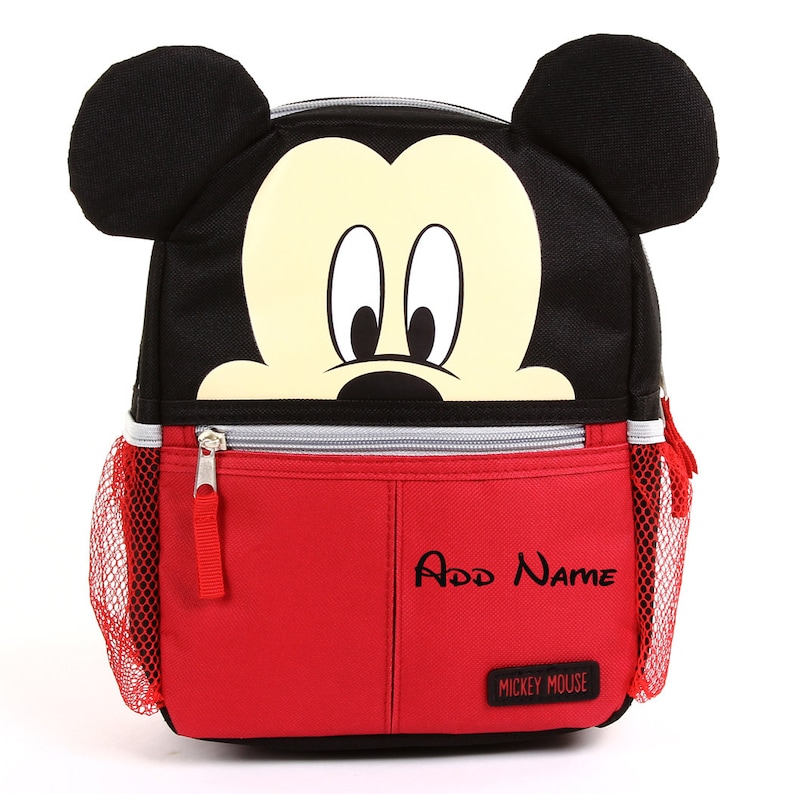 Puede incluir: Mochila de Mickey Mouse roja y negra con un bolsillo lateral de malla. La mochila tiene un bolsillo frontal con cremallera con un tirador de cremallera gris y las palabras "A&ntilde;adir nombre" impresas en negro. La parte inferior de la mochila tiene una etiqueta negra con las palabras "Mickey Mouse" impresas en blanco.