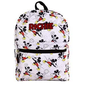 Peut inclure: Sac à dos blanc orné de motifs de Mickey Mouse en action avec des ballons de football. Le nom "RICHIE" est imprimé en rouge. Il possède une fermeture éclair et une poignée noires.