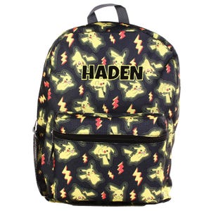 May include: Black backpack with a repeating pattern of yellow Pikachu characters and red lightning bolts. The name "HADEN" is printed in large, white block letters across the top. The backpack has a front pocket, side mesh pocket, and a grey handle.
