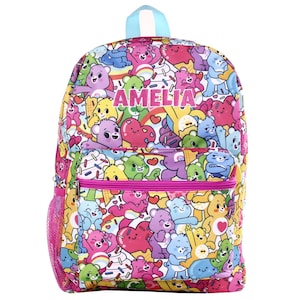 May include: A colorful backpack featuring a repeating pattern of cartoon bears, hearts, and ice cream cones. The name "AMELIA" is printed in pink across the front. The backpack has a pink mesh side pocket, a front zippered pocket, and a light blue handle.