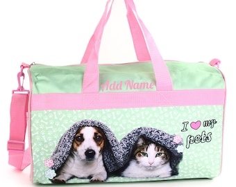 Peut inclure: Un sac de sport vert et rose avec un chien et un chat qui sortent d'une couverture. Le sac a un fond blanc avec des empreintes de pattes et des os. Le texte "J'aime mes animaux de compagnie" est imprimé sur le sac.