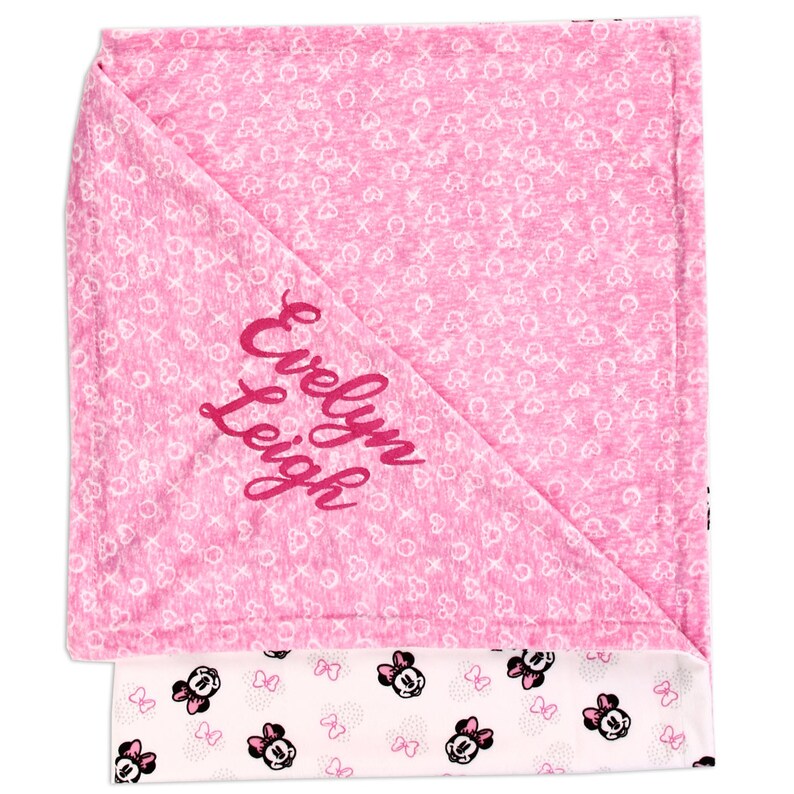 K&ouml;nnte beinhalten: Rosa-wei&szlig;e Babydecke mit einem Minnie Mouse-Design auf der einen Seite und einem rosa Hintergrund mit wei&szlig;en Herzen und dem gestickten Namen "Evelyn Leigh" auf der anderen Seite.