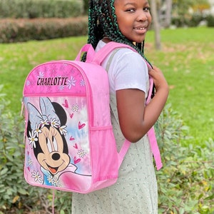 Pu&ograve; includere: Uno zaino rosa con un design di Minnie Mouse e il nome Charlotte sul davanti. Lo zaino ha una tasca a rete sul lato e una chiusura con coulisse.
