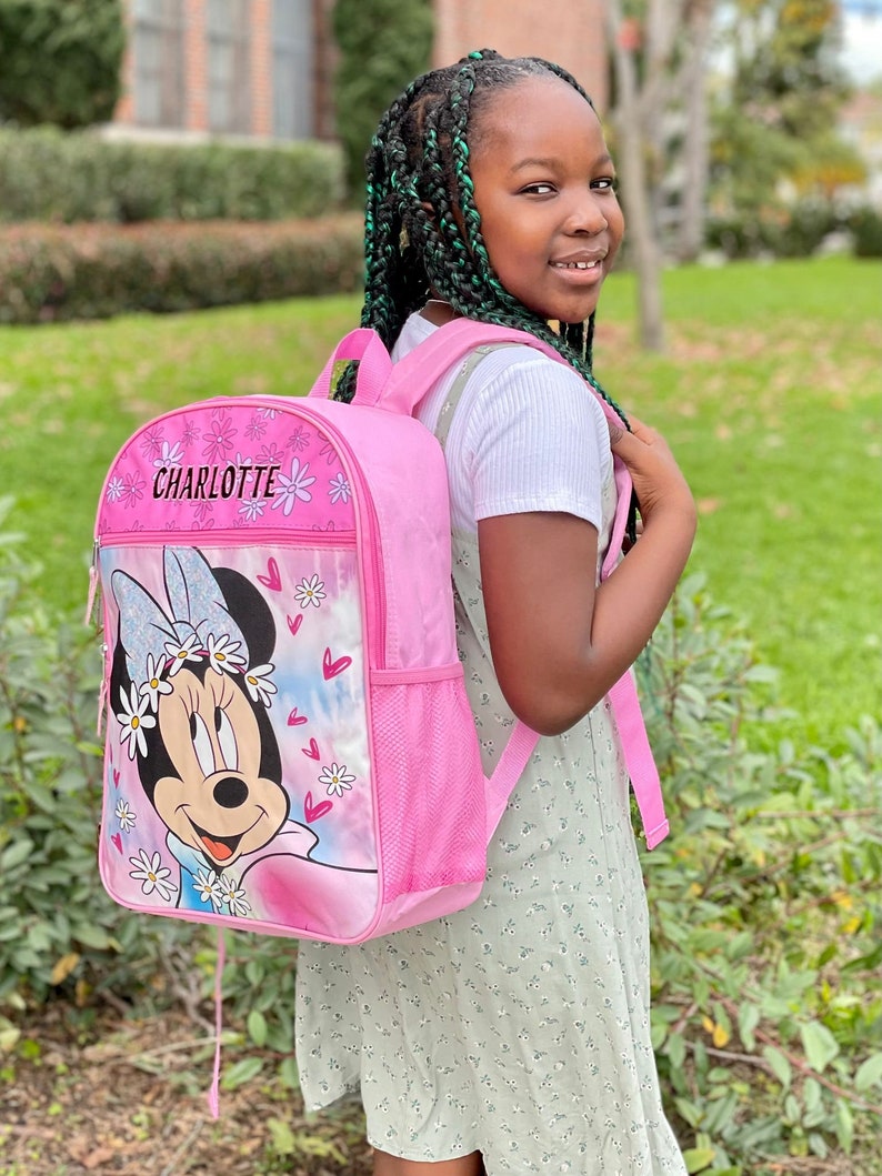 Pu&ograve; includere: Uno zaino rosa con un design di Minnie Mouse e il nome Charlotte sul davanti. Lo zaino ha una tasca a rete sul lato e una chiusura con coulisse.