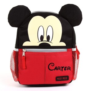 Puede incluir: Mochila de Mickey Mouse roja y negra con un bolsillo lateral de malla y un bolsillo frontal con cremallera. El bolsillo frontal tiene el nombre "Carter" escrito en &eacute;l y las palabras "Mickey Mouse" debajo.