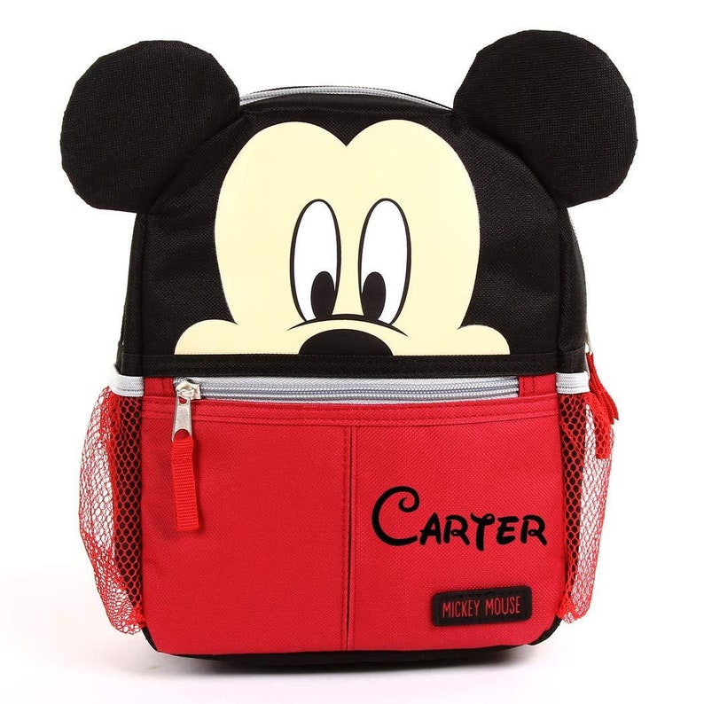 Puede incluir: Mochila de Mickey Mouse roja y negra con un bolsillo lateral de malla y un bolsillo frontal con cremallera. El bolsillo frontal tiene el nombre "Carter" escrito en &eacute;l y las palabras "Mickey Mouse" debajo.