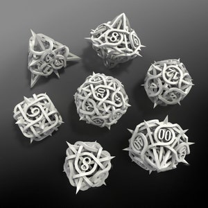 May include: Seven white, geometric dice with intricate, interwoven designs and sharp, pointed edges. Each die features numbers in a unique font. The dice are arranged on a dark gray surface, creating a striking contrast.
