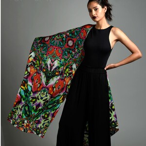 May include: A woman wearing a black tank top and wide-legged pants with a colorful patterned scarf draped over her shoulder. The scarf has a vibrant design with red, green, and purple hues. The text "SUBLIMINAL by Claudia Grattaldo" is visible at the top of the image.
