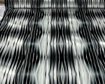 May include: A roll of fabric with a black and white geometric pattern. The design features vertical, wavy lines that create a symmetrical, abstract design. The fabric is labeled "SYMMETRIA TEXTILE PRINT DESIGN."
