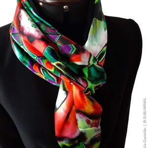 May include: A colorful silk scarf with abstract floral patterns in shades of red, green, purple, and white. The scarf is tied around a black mannequin's neck.
