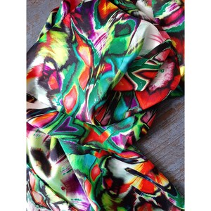 May include: A colorful abstract print fabric with shades of green, red, pink, yellow, and black. The fabric has a silky texture and is perfect for creating unique garments or accessories.