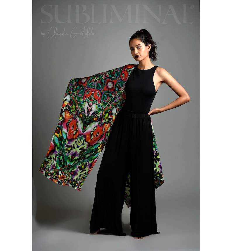 May include: A woman wearing a black tank top and wide-legged pants with a colorful patterned scarf draped over her shoulder. The scarf has a vibrant design with red, green, and purple hues. The text "SUBLIMINAL by Claudia Grattaldo" is visible at the top of the image.