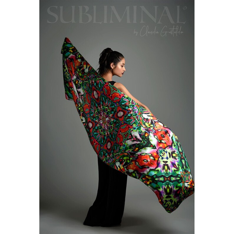 May include: A woman wearing a black dress holds a colorful silk scarf with a geometric pattern. The scarf is green, red, and white with a mandala design. The text "SUBLIMINAL by Claudia Gostaldo" is printed on a gray background.