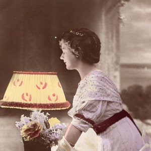 Vintage Post Card mooie dame leunend op tafel met lamp en bloemen