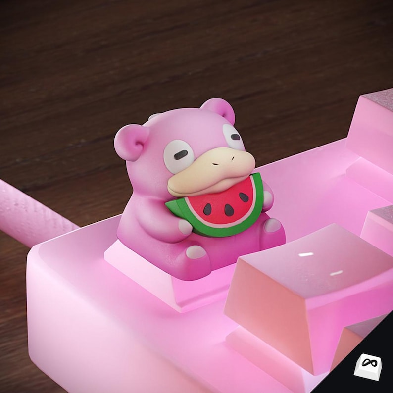 May include: A pink Slowpoke figurine holding a watermelon slice, placed on a pink keyboard. The figurine has a light beige snout and black eyes. The keyboard keys are also pink, with a black and white infinity symbol in the corner.