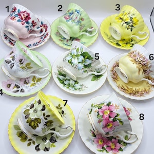 Può includere: Una collezione di otto tazze e piattini vintage. Ogni tazza e piattino presenta un diverso motivo floreale in vari colori, tra cui rosa, giallo, verde e bianco. Le tazze hanno manici delicati e sono su piattini abbinati.