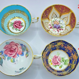 Puede incluir: Cuatro tazas de té antiguas con diseños florales. Las tazas de té presentan una variedad de colores, incluyendo azul, burdeos, blanco y azul marino. Cada taza tiene un borde y un asa dorados. Las tazas de té están decoradas con rosas y otros motivos florales.