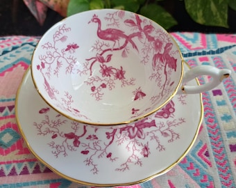 Può includere: Servizio da tè bianco con bordo dorato e motivo floreale e di uccelli rosa. La tazza ha un manico curvo e poggia su un piattino abbinato. Un set vintage per il tè.
