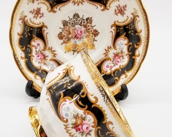 Paragon teacup and saucer - black panels on white background , florals and gold detailing