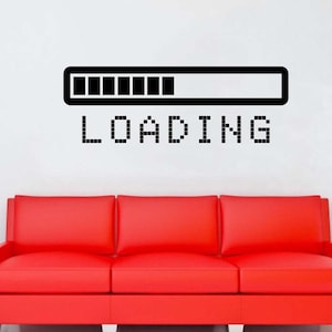 May include: A black wall decal featuring a rectangular progress bar with eight filled segments and the word LOADING in a pixelated font. The decal is positioned above a bright red three-cushion sofa in a room with a black vase and a floor lamp.