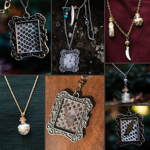 Könnte beinhalten: Eine Sammlung handgefertigter Halsketten. Die Anhänger zeigen verschiedene Designs, darunter gerahmte Reptilienhaut, getrocknete Blumen und kleine Glasflaschen, die mit natürlichen Elementen gefüllt sind. Die Halsketten haben silberne und goldene Ketten, einige enthalten dekorative Perlen und Charms.