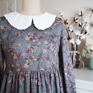 May include: A blue and pink floral dress with a white peter pan collar. The dress has long sleeves and a gathered skirt.