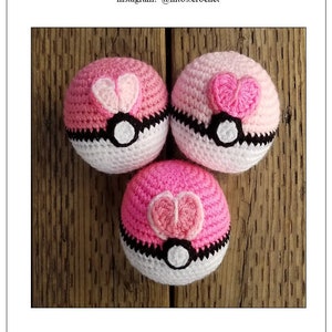 May include: Three crocheted Pokeball Loveballs in pink, white and black. Each ball has a heart-shaped design on the top.